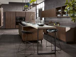 Die Insel wird von zwei Thekenflügeln aus Keramik eingerahmt. So sind die Wege zwischen Spülen und Kochen kurz. «Y-line» in «Terrazzo goldbraun» und «Sherwood dunkelbraun». Hans Eisenring AG.