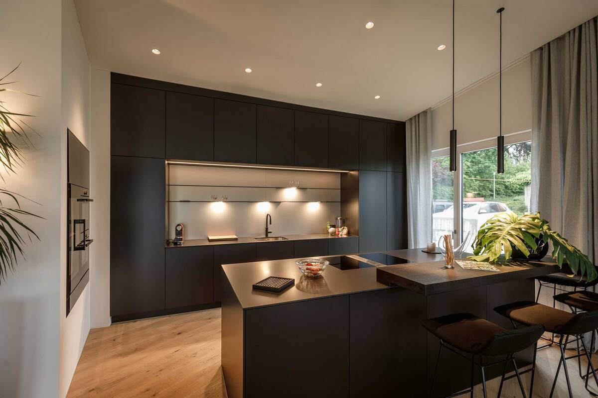 Die Küche «Orea X» besticht durch ihre dunkle Farbe. Die helle Rückwand sorgt für den gelungenen Kontrast. Foto: Andre Herger Fotografie GmbH. Orea AG.