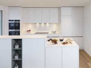 Grifflose Fronten, hier in Weiss «Porzellan», geben der weissen Küche noch mehr Eleganz. Die LED-Beleuchtung sorgt fürs richtige Licht. Alpnach Norm.