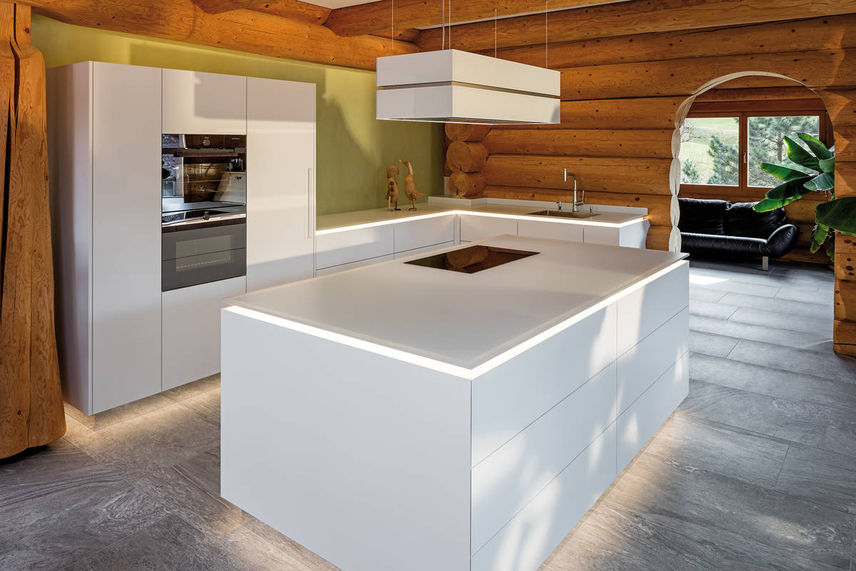 Geradlinig und modern. Die Arbeitsfläche aus Glas wirkt durch LED-Beleuchtung wie schwebend auf der Kücheninsel. Furrer Küchen.