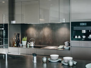 Perfekte Harmonie: Die grauen hochglänzenden Fronten «Rainbow» passen zur Arbeitsfläche aus Keramik. Herzog Küchen AG.