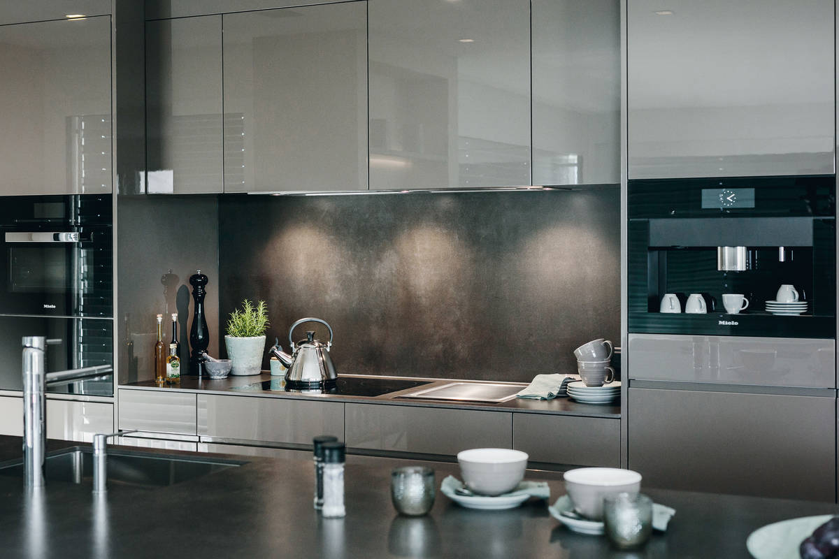Perfekte Harmonie: Die grauen hochglänzenden Fronten «Rainbow» passen zur Arbeitsfläche aus Keramik. Herzog Küchen AG.