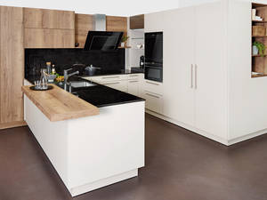 Die Schwarz-Weiss Kombi der Küche wird durch die edlen Holzoptik-Elemente gebrochen. Die intelligente Abzugshaube sorgt für das technische Highlight. Sabag.