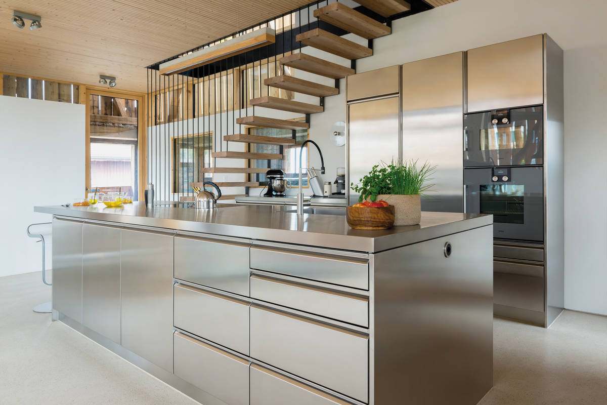 Die Kücheninsel aus Edelstahl sorgt für modernen Industrie-Charakter in der heimischen Küche. Die Griffleisten sind dezent und bringen Struktur auf die Front. Tiba AG.
