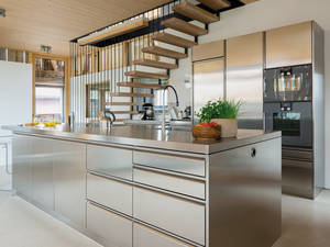 Die Kücheninsel aus Edelstahl sorgt für modernen Industrie-Charakter in der heimischen Küche. Die Griffleisten sind dezent und bringen Struktur auf die Front. Tiba AG.