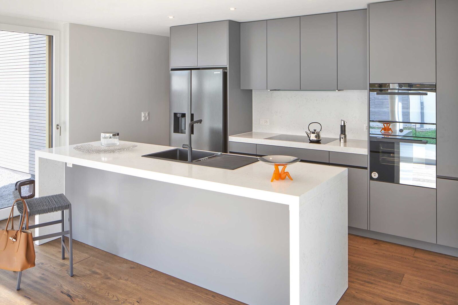 Die schwarzer Griffleiste setzt einen schönen Akzent zum Grau und harmoniert mit den dunklen Küchengeräten.