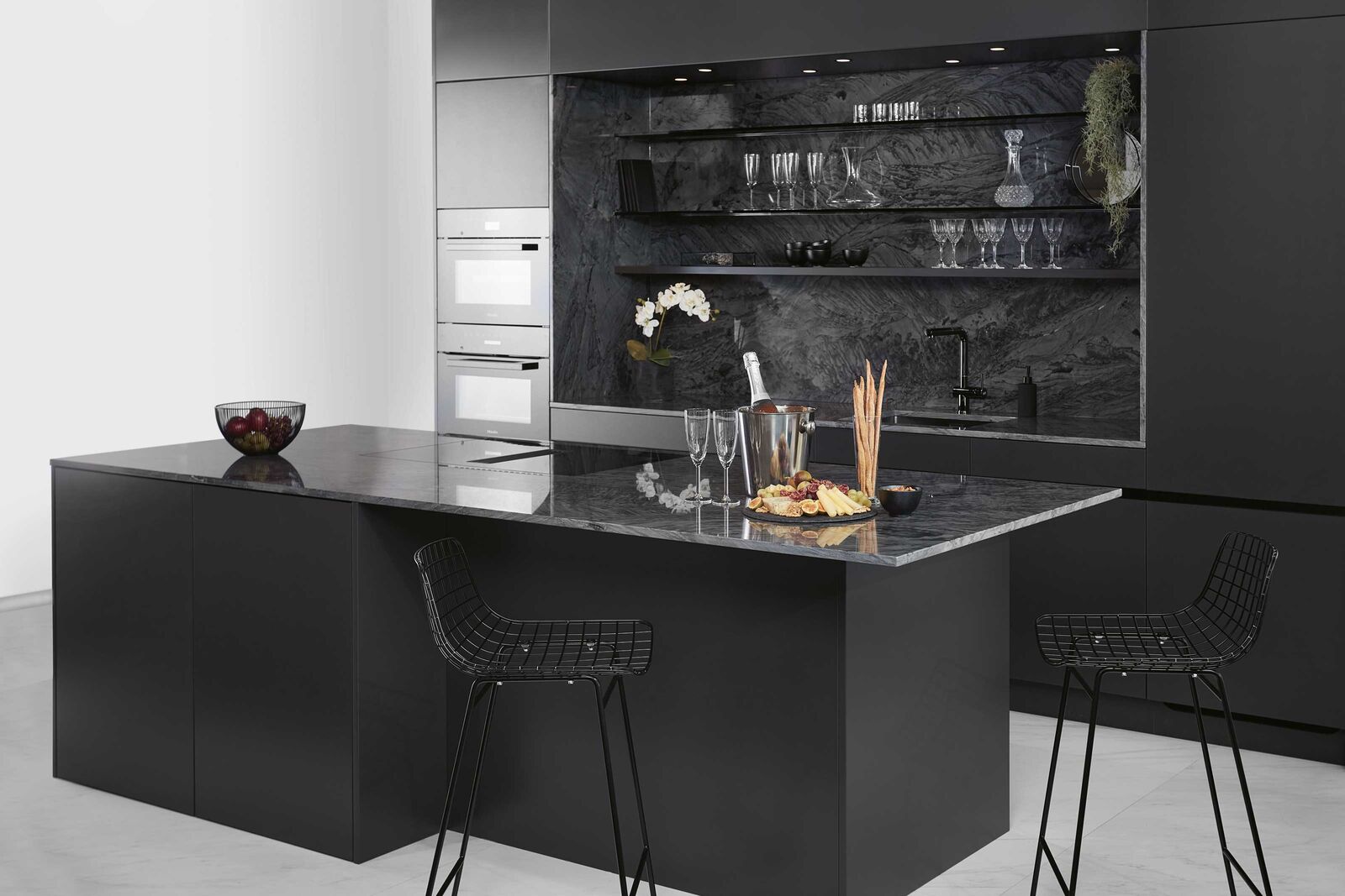 Elegant und glamourös In dieser Stilwelt werden edle Materialien stilvoll in Szene gesetzt: Der polierte Granit glänzt in dieser Küche nicht nur als klassi­sche Abdeckung, sondern auch als Nischenverkleidung. Tablare aus Rauchglas und strukturlackierte Fronten bieten ihm die ideale Bühne und machen aus dem Zentrum des Hauses ein Schmuckstück.