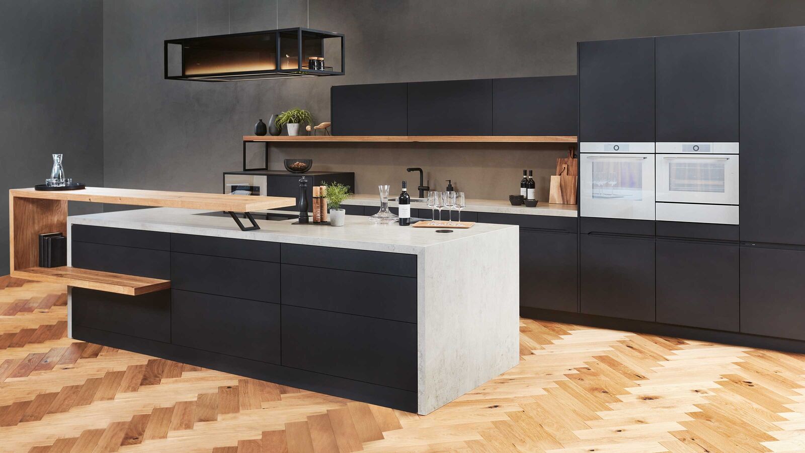 Puristisch und zeitlos Hier sind zeitlose Materialien gefragt, schlichtes Designs und Oberflächen mit genau jenem Farbton, der das Ensemble perfekt macht. Passend zu Bauten, die einen universellen Designanspruch abdecken. Die Küchenmöbel aus der «Infinity»-Linie zeichnen sich durch höchste Qualität und Langlebigkeit aus. Hergestellt aus kompakt verdichteten Faserplatten aus Schweizer Holz, sind sie be­sonders nachhaltig. Mattschwarze Armaturen, ein edler Weinkühler sowie silberfarbene Öfen runden das Ensemble ab.