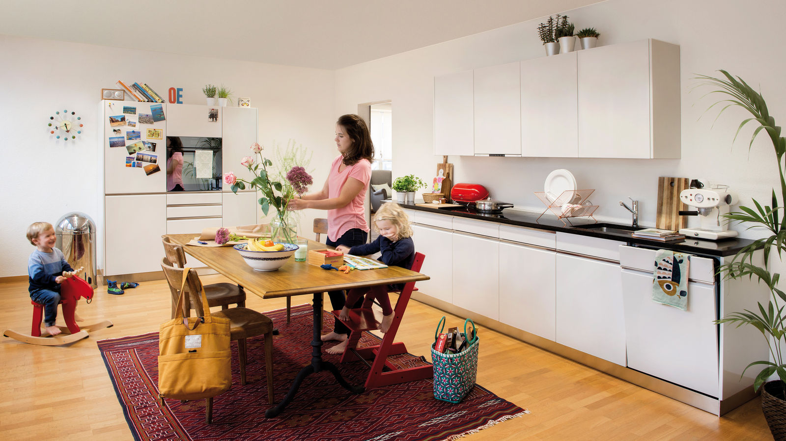  Küche in Alpinweiss mit Griffleisten in Edelstahl und Steinabdeckung.